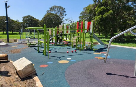 A photo of an outdoor play equipment area within a larger park