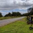 A photo of a group of three people on bikes on the side of a country road.