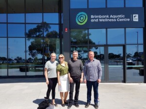 A group of four people standing outside a building posing for a group photo