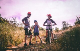 A photo of a man and two children on bikes on a trail