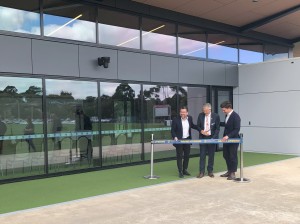 An image of three men standing in front of a building cutting a ribbon.